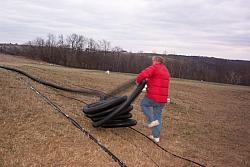Dick K0MN rolling out 4 inch drain tile that will be buried in trench.